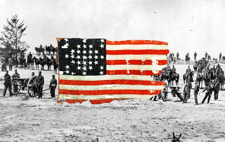 Historical photograph of a large American flag held in an open field